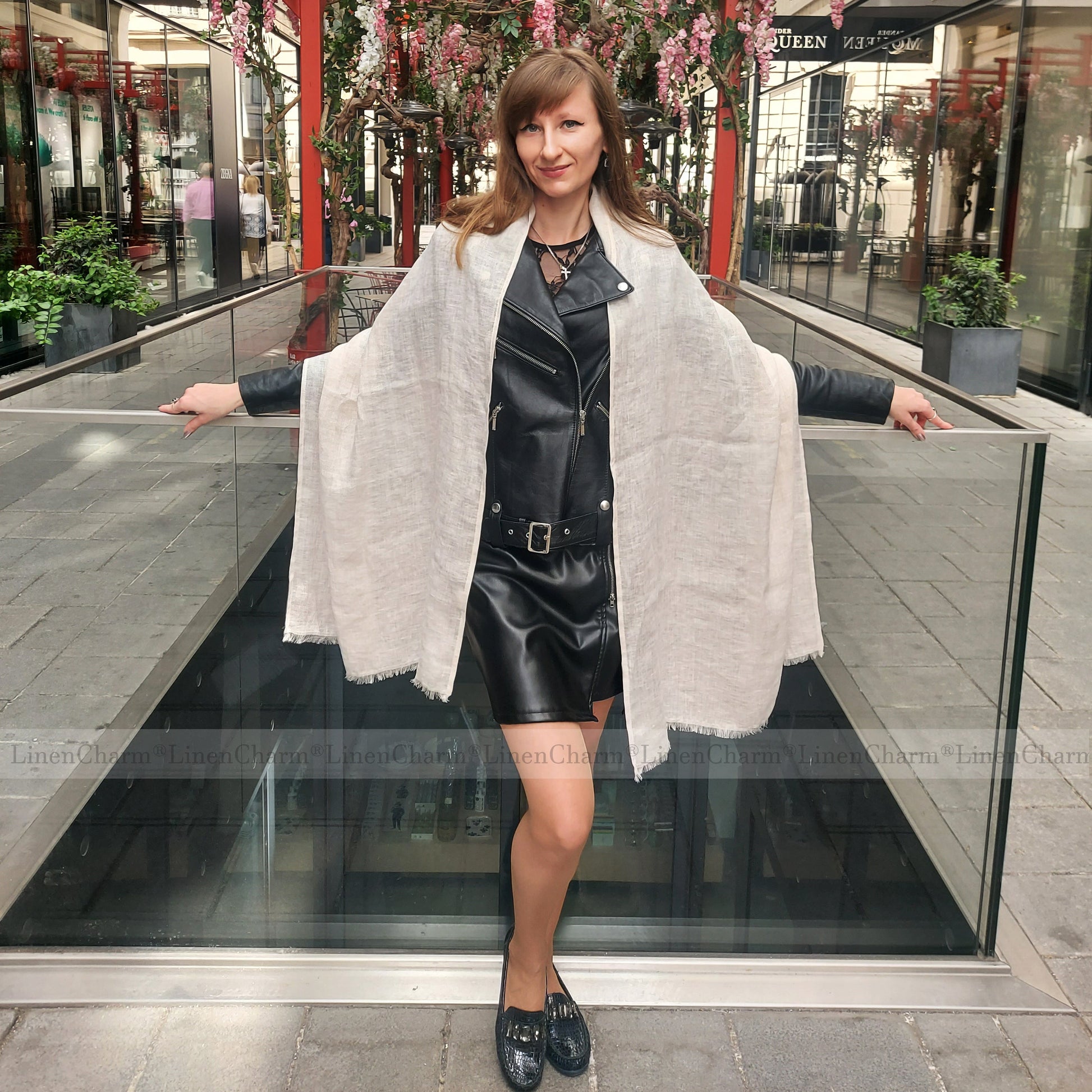 Woman standing in front of a decorative entrance with wearing a black outfit and white shawl.