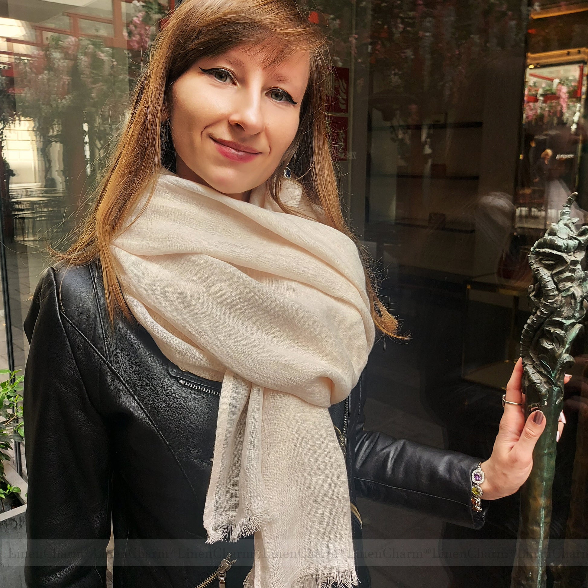 Woman wearing a beige scarf in an indoor setting with blurred background