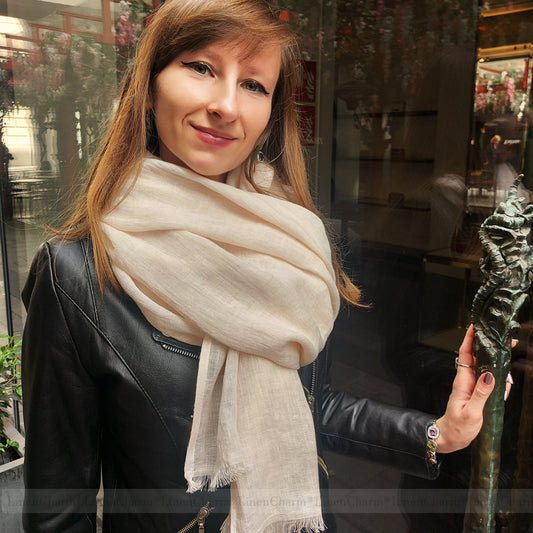 Woman wearing a beige scarf in an indoor setting with blurred background
