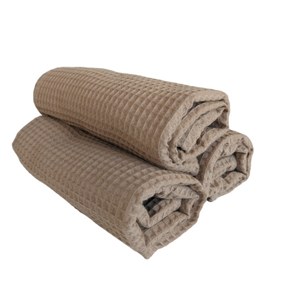 Two folded beige textured blankets on a white background