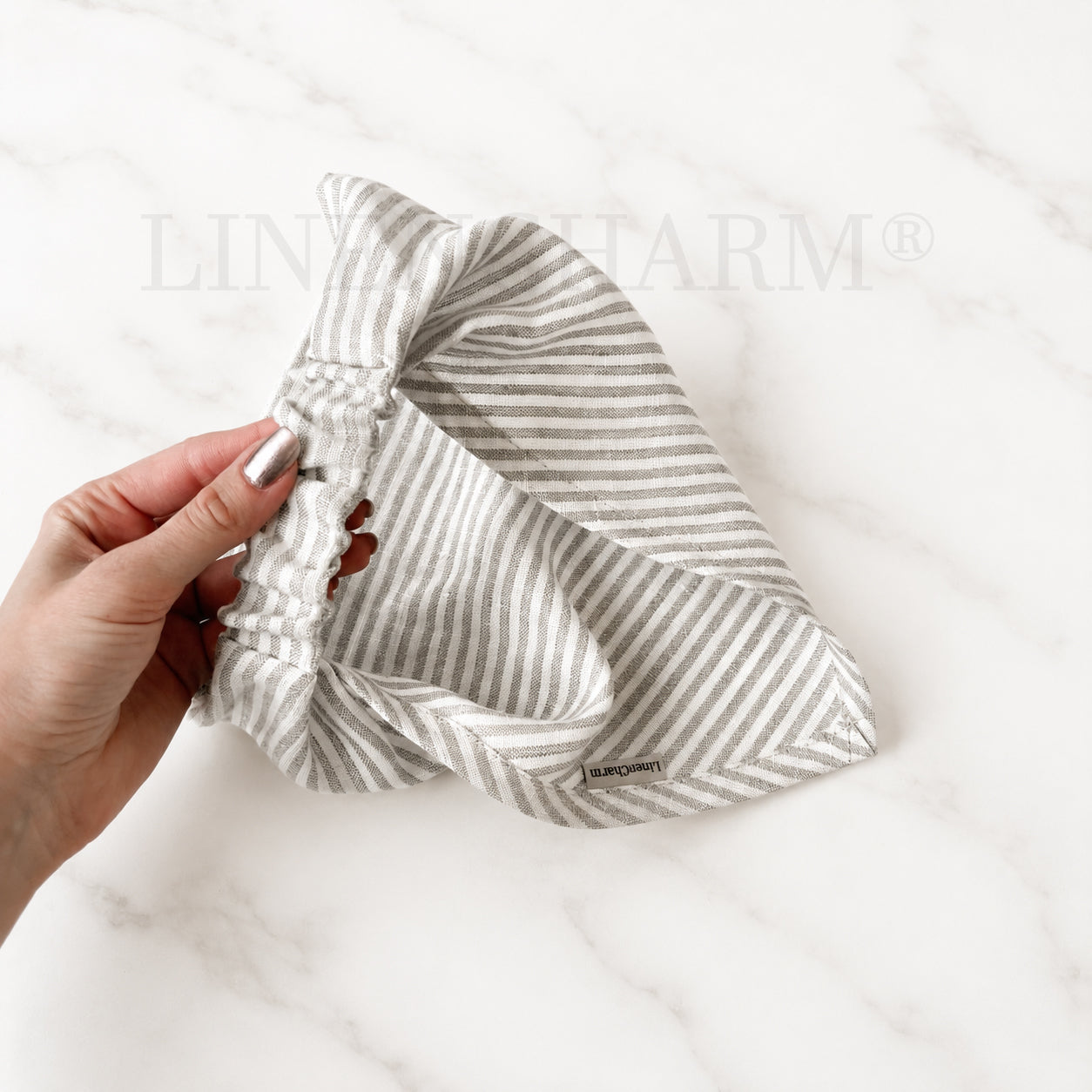 Striped headband held by a hand on a white background with 'ELIN JARM' branding.