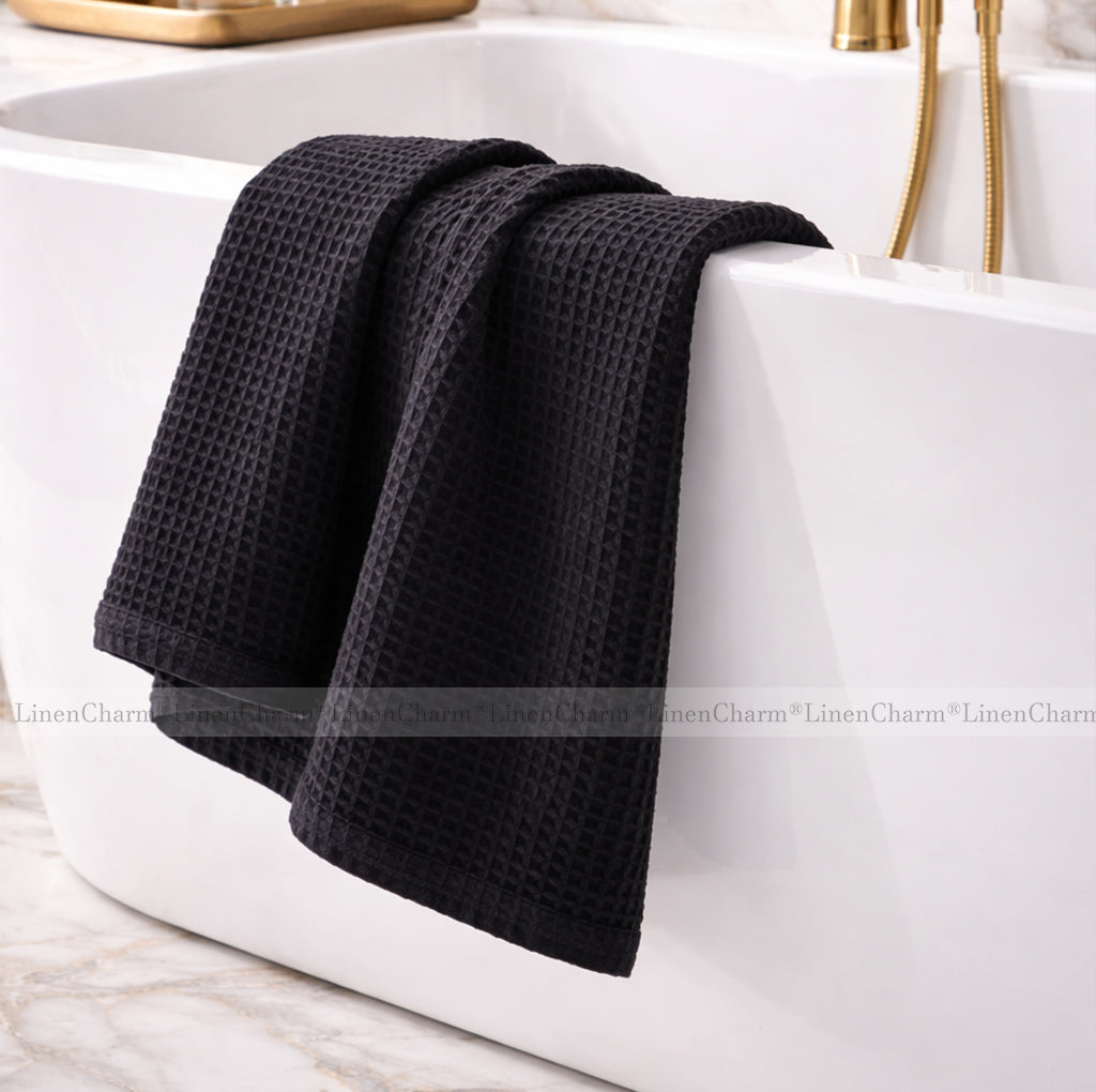 Black waffle-textured towel draped over a white bathtub.