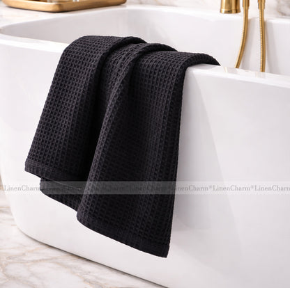 Black waffle-textured towel draped over a white bathtub.