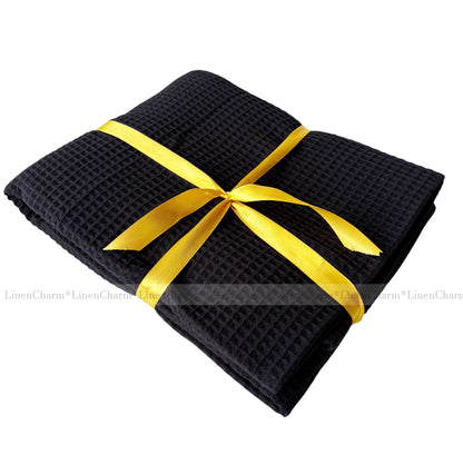 Black folded towel with a yellow ribbon on a white background