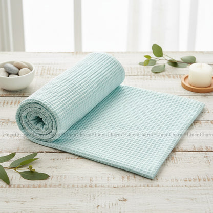 Light mint  textured towel rolled out on a wooden surface with decorative elements.