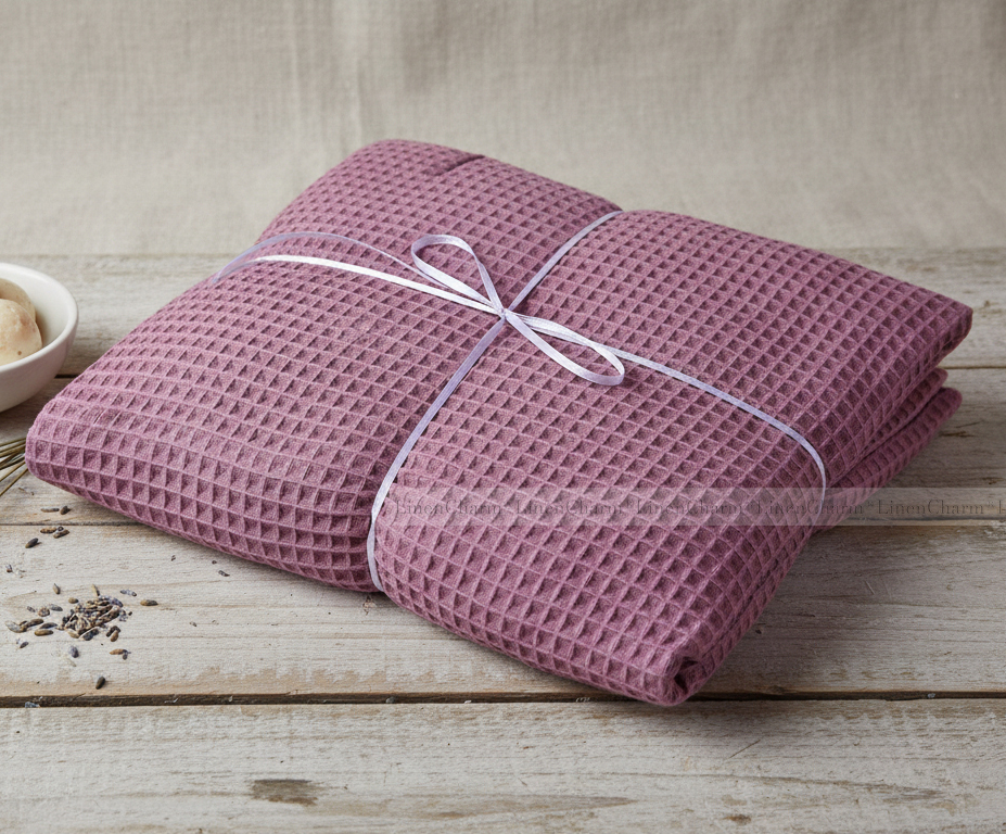 Folded pink textured blanket tied with a white ribbon on a wooden surface.