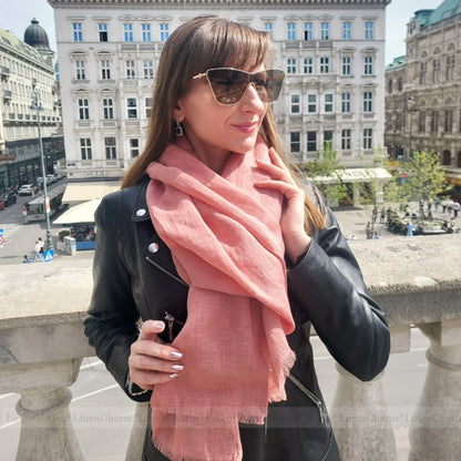 Woman wearing a salmon pink scarf and sunglasses in an urban setting