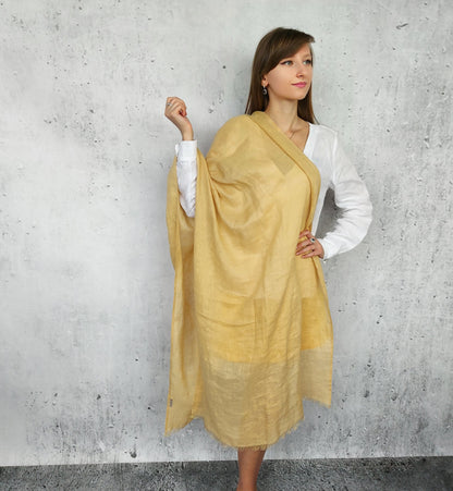 Woman wearing a linen beige sand scarf against a gray concrete wall