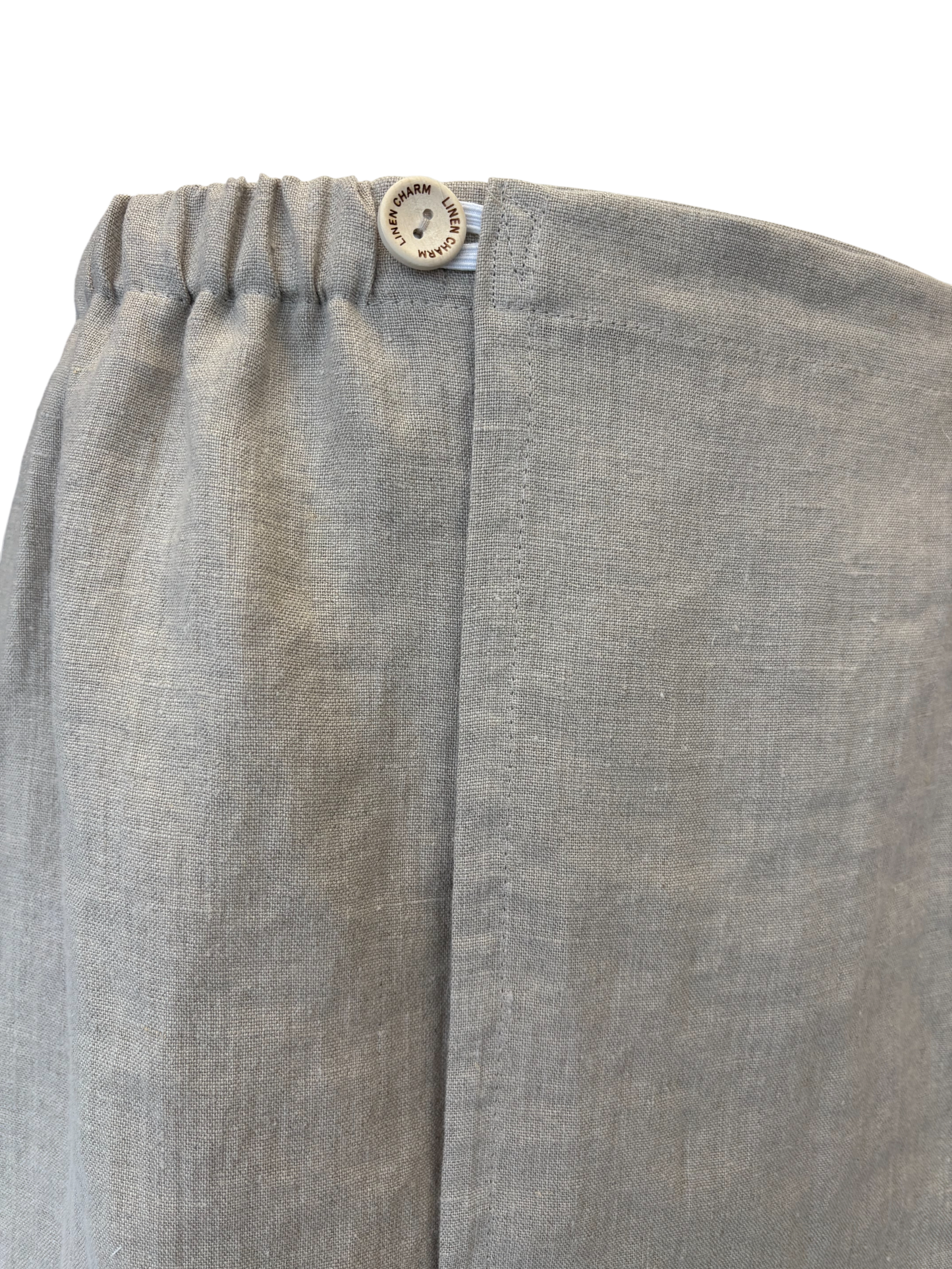 Close-up of gray pants with a button on a white background