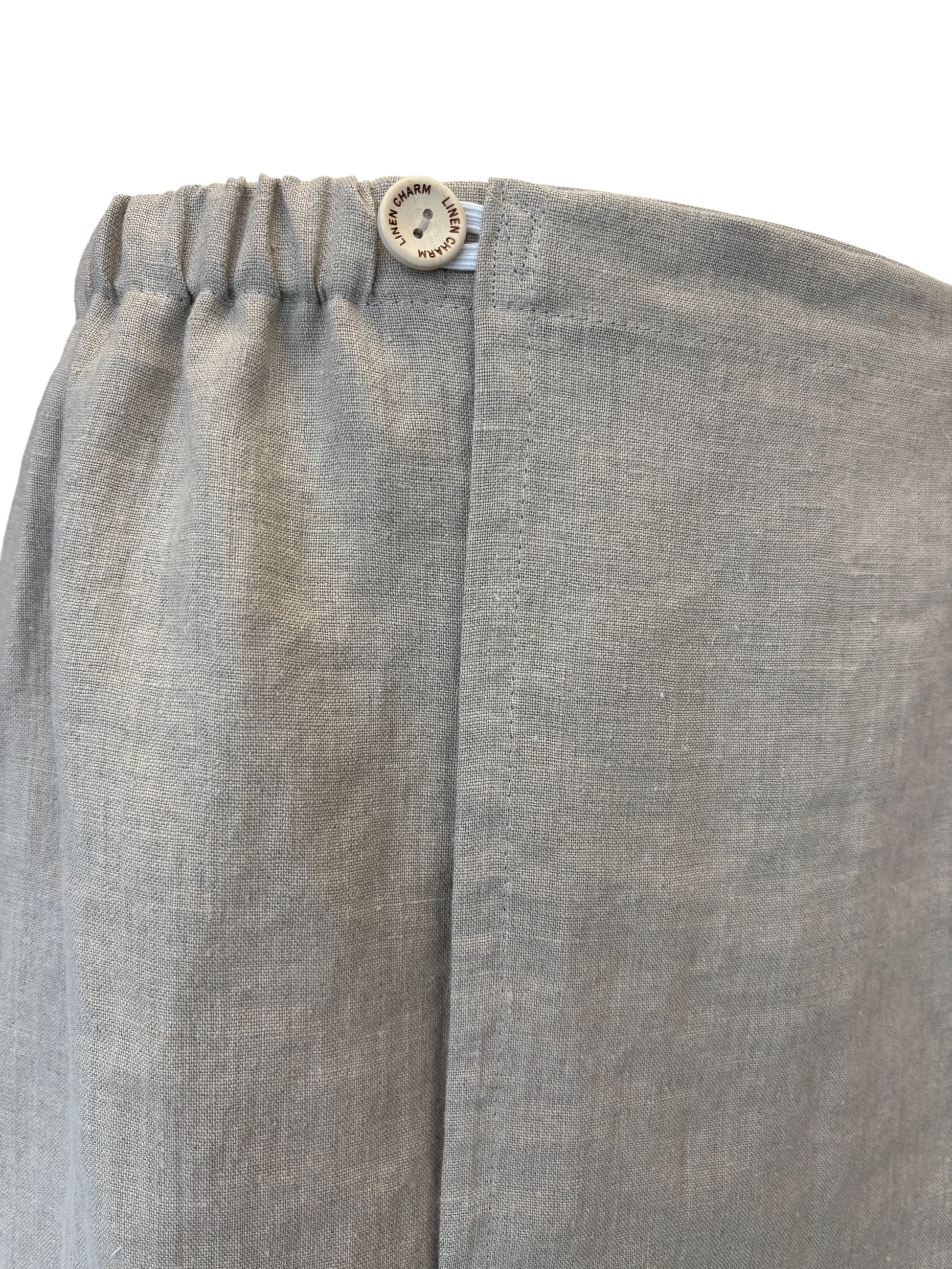Close-up of gray pants with a button on a white background