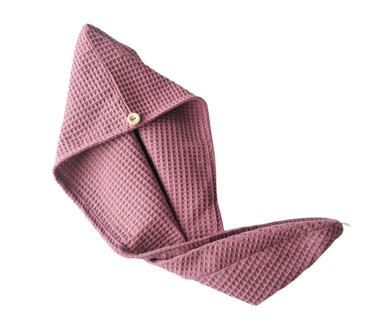 Pink waffle-textured towel with a button on a white background