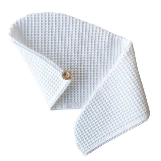 White waffle-textured baby blanket with a wooden button on a white background