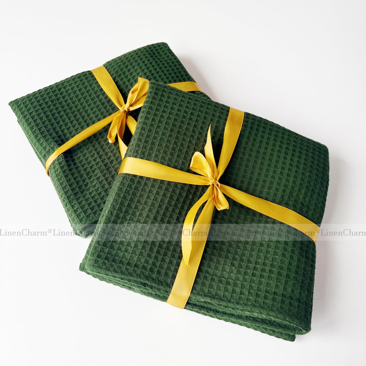 Two green waffle-textured towels with yellow ribbons on a white background
