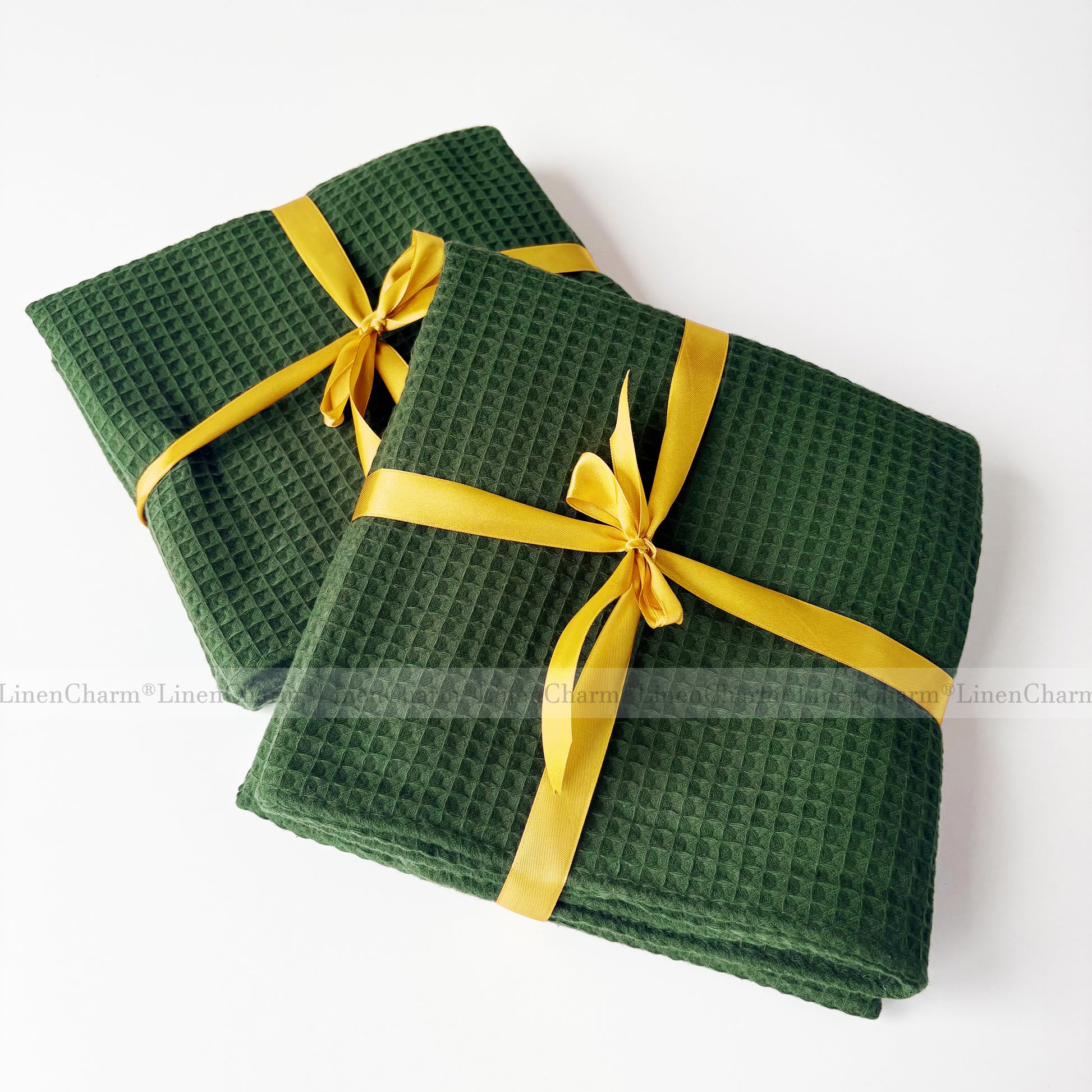 Two green waffle-textured towels with yellow ribbons on a white background