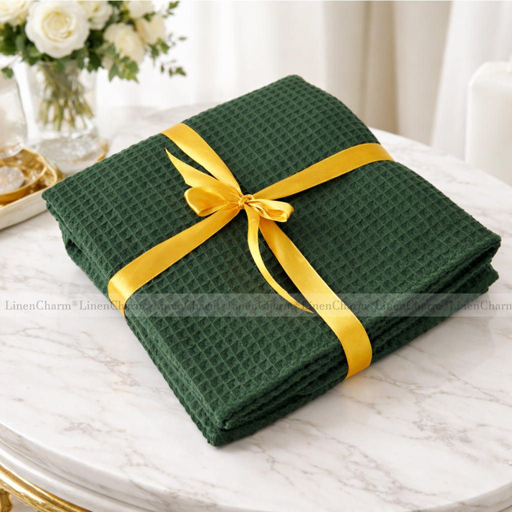 Green folded fabric with a yellow ribbon on a marble surface, with 'LinenCharm' branding.