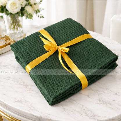 Green folded fabric with a yellow ribbon on a marble surface, with 'LinenCharm' branding.